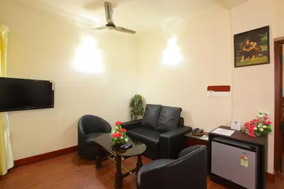 a living room with a couch and chairs and a tv at Trichur Towers in Trichūr