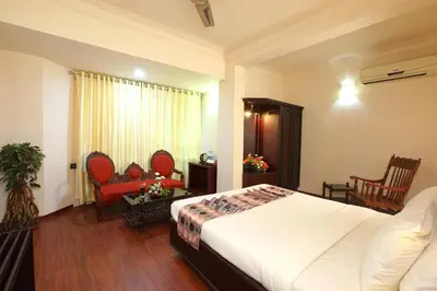 a bedroom with a large white bed and chairs at Trichur Towers in Trichūr