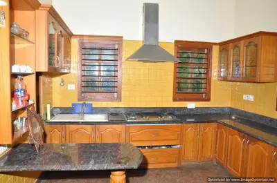 a kitchen with a sink and a stove top oven at Suvarna Luxury Home Stay in Mysore
