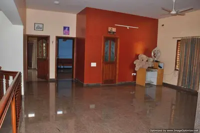 a living room with red walls and a teddy bear on a table at Suvarna Luxury Home Stay in Mysore