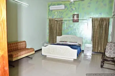 a bedroom with a bed and a couch and a chair at Suvarna Luxury Home Stay in Mysore
