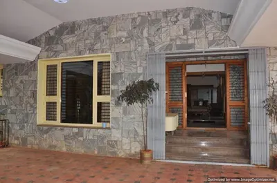 a house with a stone wall with a tree on it at Suvarna Luxury Home Stay in Mysore