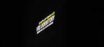 a sign that is lit up in the dark at vrs dormitary in Mysore