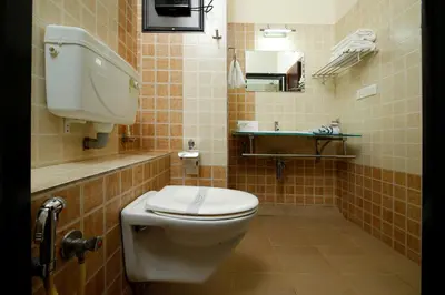 a bathroom with a white toilet and a sink at Rose International Hotel in Nilambūr