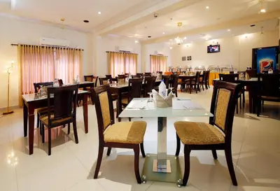 a dining room with tables and chairs in a restaurant at Rose International Hotel in Nilambūr