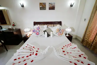 a bedroom with a white bed with red heart pillows at Rose International Hotel in Nilambūr