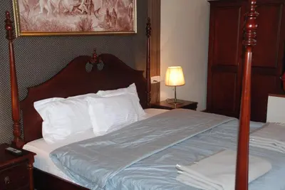 a bedroom with a large bed with a wooden headboard at Colonial 4 B/R Home, Great for Families, Coonoor in Coonoor