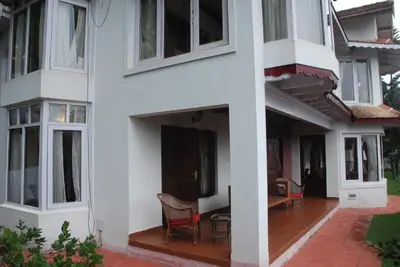 a white building with chairs and a table at Colonial 4 B/R Home, Great for Families, Coonoor in Coonoor