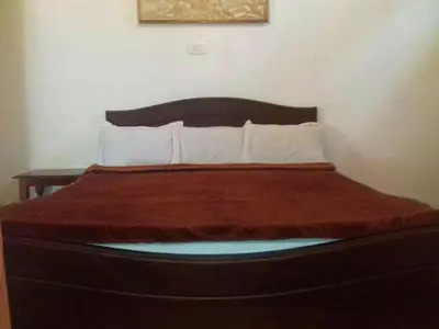 a bedroom with a large bed with a wooden headboard at Colonial 4 B/R Home, Great for Families, Coonoor in Coonoor