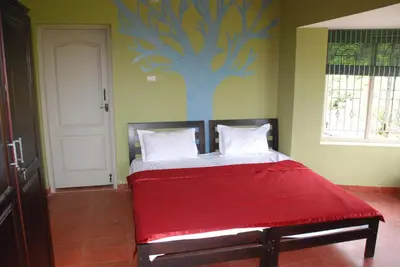 a bed in a room with a tree painted on the wall at Relaxing 2 B/R Estate House, Deenaty, Tamil Nadu in Coimbatore