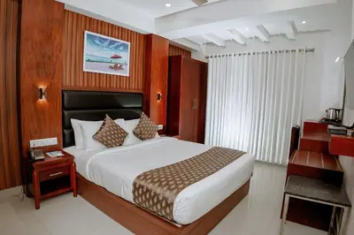 a hotel room with a bed and a desk and a bed sidx sidx at Queens Hotel in Kozhikode