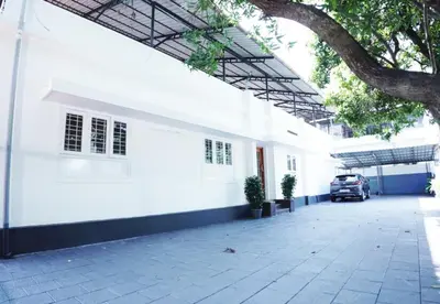 a white building with a car parked in front of it at Queens Hotel in Kozhikode