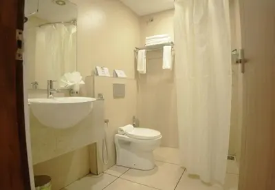 a white bathroom with a sink and a toilet at Queens Hotel in Kozhikode