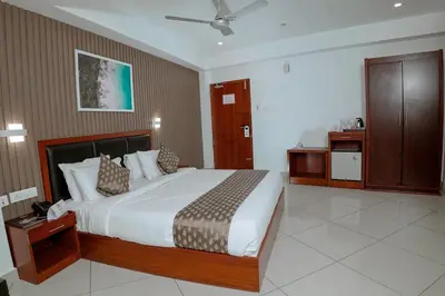 a bedroom with a large bed and a bathroom at Queens Hotel in Kozhikode