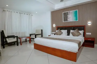 a hotel room with a large bed and a chair at Queens Hotel in Kozhikode
