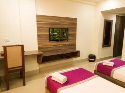 a room with two beds and a tv on the wall at Nexstay Crystal Residency in Kozhikode