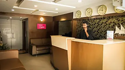a man talking on a cell phone behind a counter at Nexstay Crystal Residency in Kozhikode