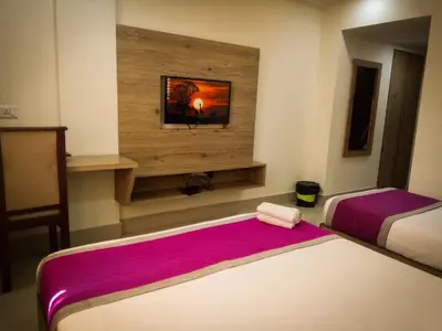 a room with two beds and a tv on the wall at Nexstay Crystal Residency in Kozhikode