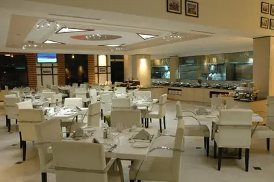 a dining room with white tables and white chairs at Sandesh The Prince in Mysore