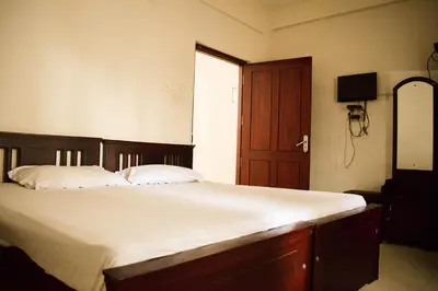 a bedroom with a large bed with white sheets and a door at Ruby Residency in Kozhikode