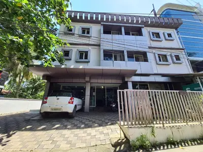 a white car parked in front of a building at Ruby Residency in Kozhikode