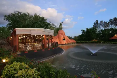 a building with a fountain in front of a pond at Silent Shores Resort & Spa in Mysore