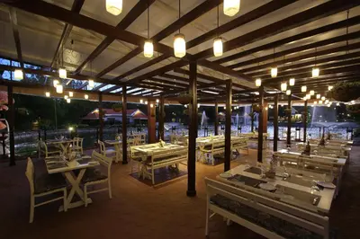 a restaurant with tables and chairs and lights at Silent Shores Resort & Spa in Mysore