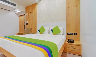 a bedroom with a white bed with a rainbow blanket at Treebo Vinayak Inn, 600 Mts From Coimbatore Railway Station in Coimbatore