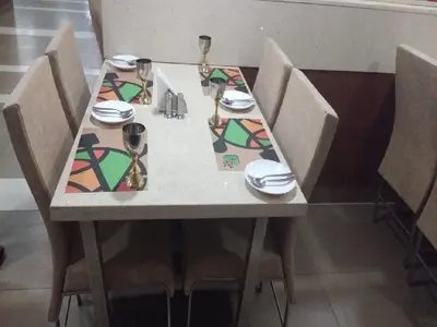 a table with four chairs and a table with plates and glasses at Hotel iStay in Coimbatore