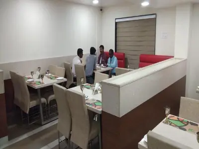 a group of people sitting at tables in a restaurant at Hotel iStay in Coimbatore