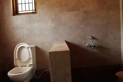 a bathroom with a toilet and a sink at Rustling River Resort in Ooty