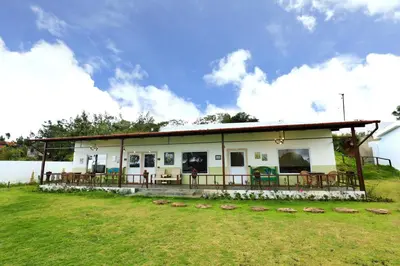 a house with a porch and a grass field at 7 BHK Luxury Heritage Villa - Rock Ooty in Ooty