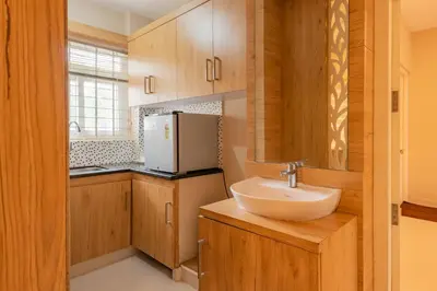 a kitchen with a sink and a refrigerator at Daan Ambalath Maple Leaves in Guruvāyūr
