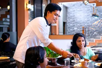 a man holding a plate of food at a restaurant at Paddyfield Inn in Mananthavady
