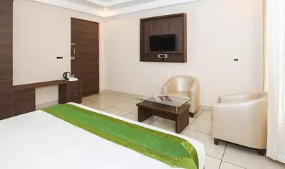 a hotel room with a bed and a chair and a tv at Treebo Durga Boji Grand, Gonikoppal Town in Gonikoppal