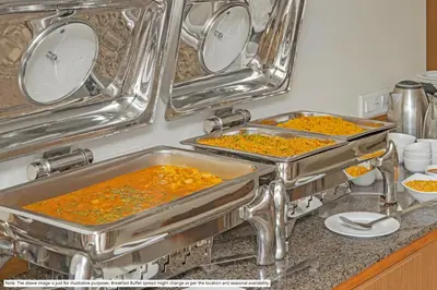 two metal pans filled with food on a kitchen counter at Treebo Durga Boji Grand, Gonikoppal Town in Gonikoppal