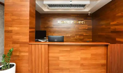 a reception desk with a sign on a wooden wall at Treebo Durga Boji Grand, Gonikoppal Town in Gonikoppal