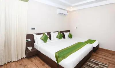 a bedroom with a large bed with green pillows at Treebo Durga Boji Grand, Gonikoppal Town in Gonikoppal