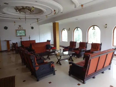 a room with chairs and a table and windows at Hotel Lakeview in Ooty