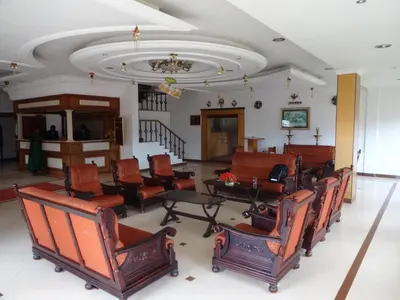 a room with chairs and tables and a ceiling at Hotel Lakeview in Ooty