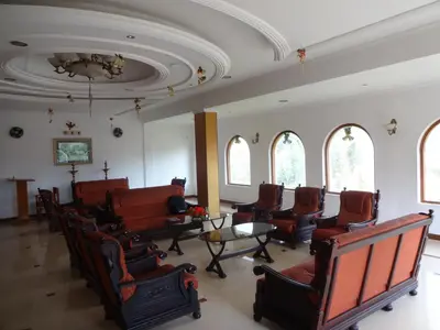 a waiting room with chairs and a table and windows at Hotel Lakeview in Ooty