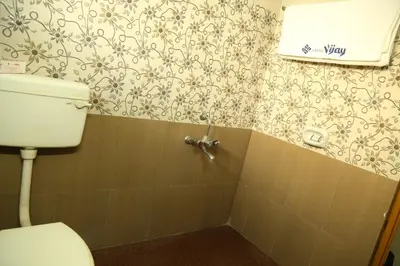 a bathroom with a toilet and a wall at Hotel Vijay in Pollāchi