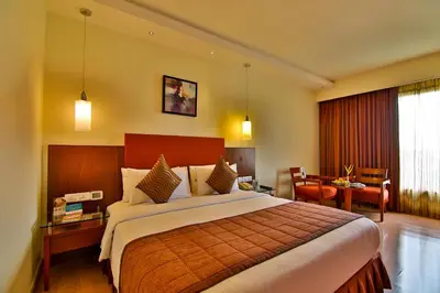 a hotel room with a large bed and a desk at Gokulam Park Coimbatore in Coimbatore