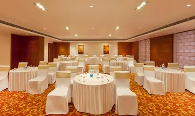 a banquet hall with white tables and white chairs at Gokulam Park Coimbatore in Coimbatore