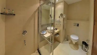 a bathroom with a shower with a toilet and a sink at Gokulam Park Coimbatore in Coimbatore