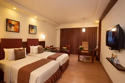 a hotel room with two beds and a television at Gokulam Park Coimbatore in Coimbatore