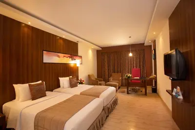 a hotel room with two beds and a television at Gokulam Park Coimbatore in Coimbatore