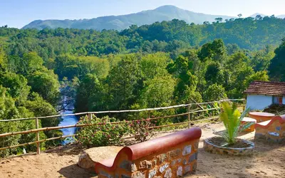 a bench sitting on top of a hill overlooking a river at Elephant Valley Eco Farm Hotel in Kodaikānāl