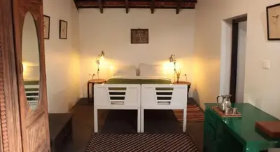 a bedroom with a white bed and a mirror at Elephant Valley Eco Farm Hotel in Kodaikānāl