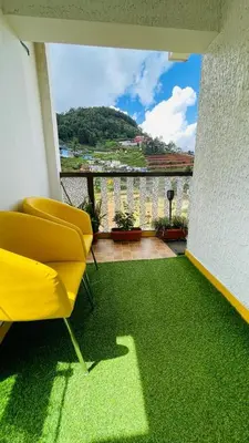 a living room with a yellow chair and green carpet at Sunset Valley Holiday Inn in Ooty